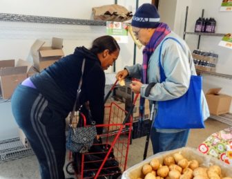 Cheryl Ware, a volunteer at the Bright Temple AME Church in Hunts Point, places food into a woman's cart at the church's weekly pantry. 