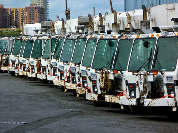 Department of Sanitation garbage trucks sit idle in a parking lot. 