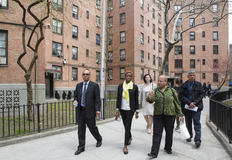 NYCHA's Olatoye (center, with yellow scarf) at a 2014 tour of the Queensbridge Houses. One bright spot for NYCHA -- a new plan to extend the hours during which tenants can get service visits -- has become embroiled in a dispute with a labor union.