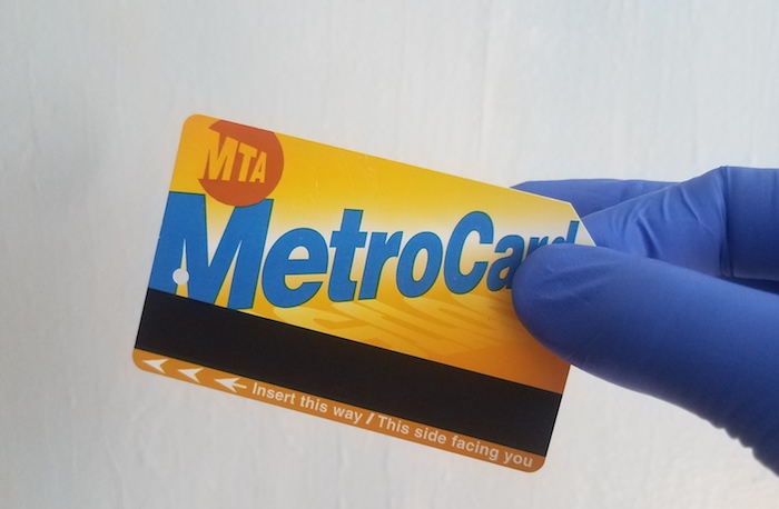 gloved hand holds metrocard