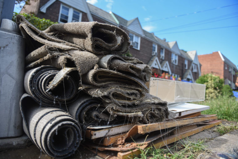 debris piled up outside of flooded homes in Queens