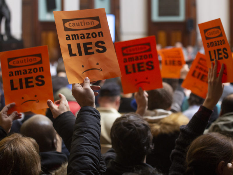 Protest signs against Amazon at a NYC Council hearing in 2019