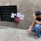 John Grima kneels near a memorial for a homeless friend who dies