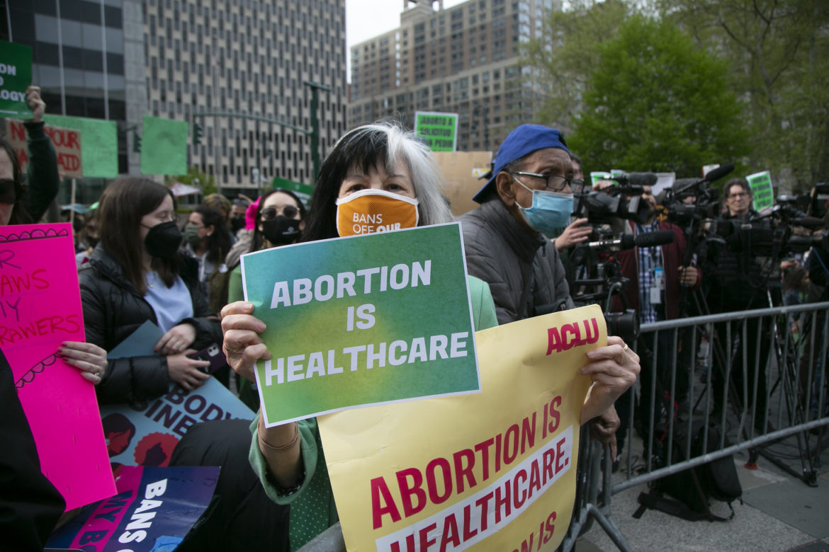 A woman at a reproductive rights rally holds a sign that says "abortion is healthcare"