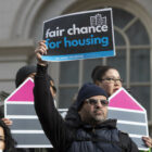 A man holds a sign at a December 2022 rally in support of the Fair Chance for Housing bill.